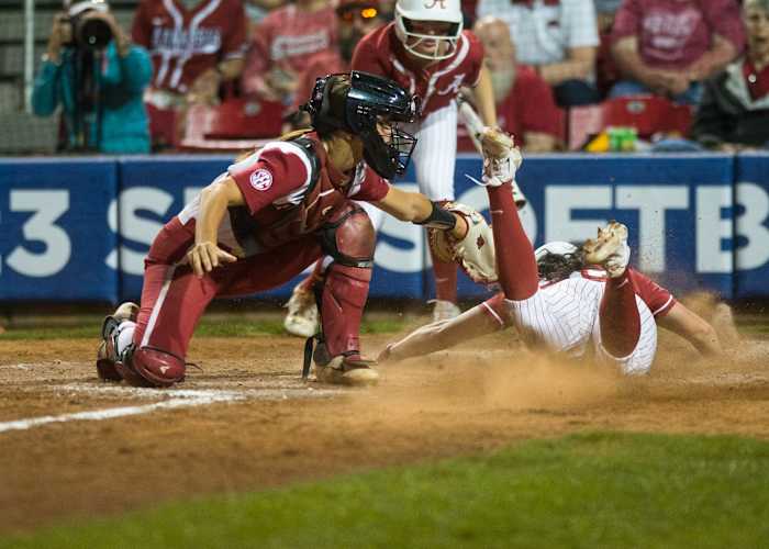 Alabama Crimson Tide outfielder Faith Hensley (23) is tagged out by Arkansas Razorbacks catcher Lauren Camenzind (8) during a quarterfinal game of the SEC Softball Tournament.